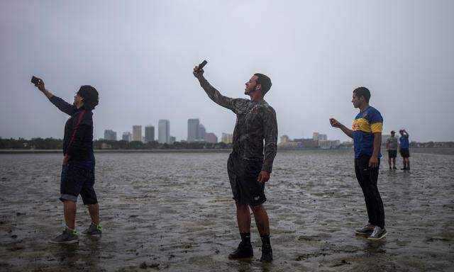 The Tampa skyline is seen in the background as local residents take photographs after walking into Hillsborough Bay ahead of Hurricane Irma in Tampa