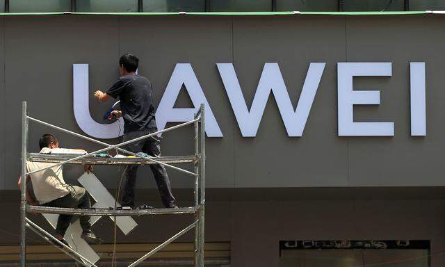 Workers put up a sign for a new Huawei store under construction in Kunming