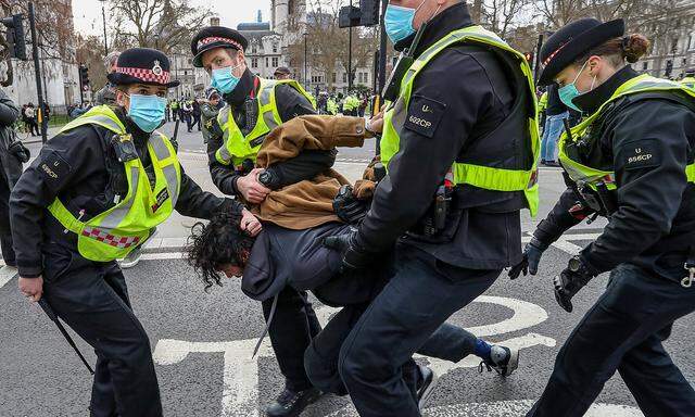 A female police officer of the city of London forcefully pulls the hair of a restrained demonstrator during clashes fol