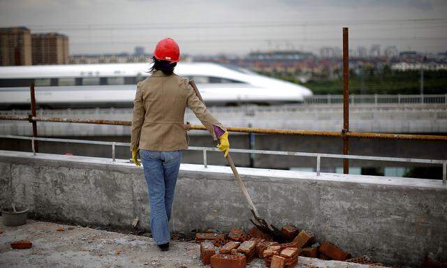 A worker watches train pass on new high-speed railway line between Shanghai and Hangzhou on the outskirts of Shanghai