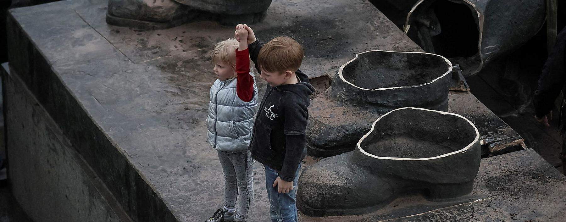 Children depict a Soviet monument to a friendship between Ukrainian and Russian nations after its demolition in central Kyiv