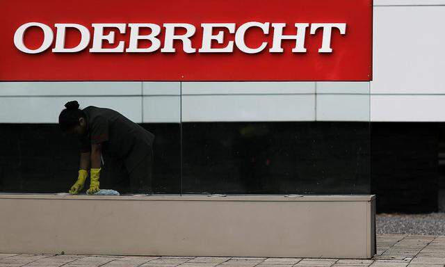 A worker cleans the corporate logo of the Odebrecht SA construction conglomerate at its headquarters in Sao Paulo