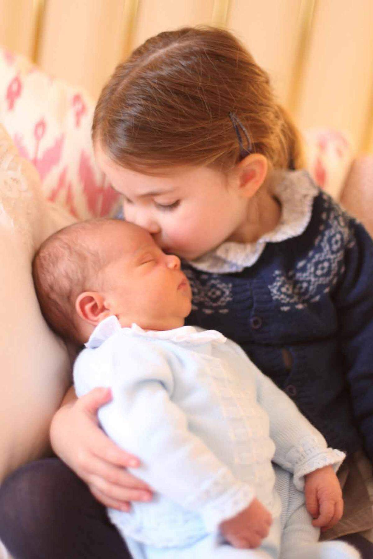 Auf einem der ersten Bilder des Nachwuchses wird der kleine Prinz von seiner Schwester, Prinzessin Charlotte, auf die Stirn geküsst.