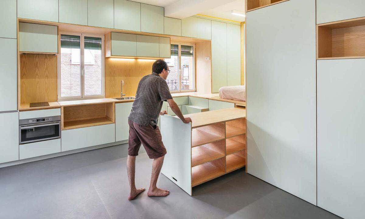 Die Ebene der Schlafkoje geht direkt in die Arbeitsplatte der Küche über, die sich seitlich im Wohnzimmer erstreckt. Hinter jeder Front versteckt sich unsichtbarer Stauraum.