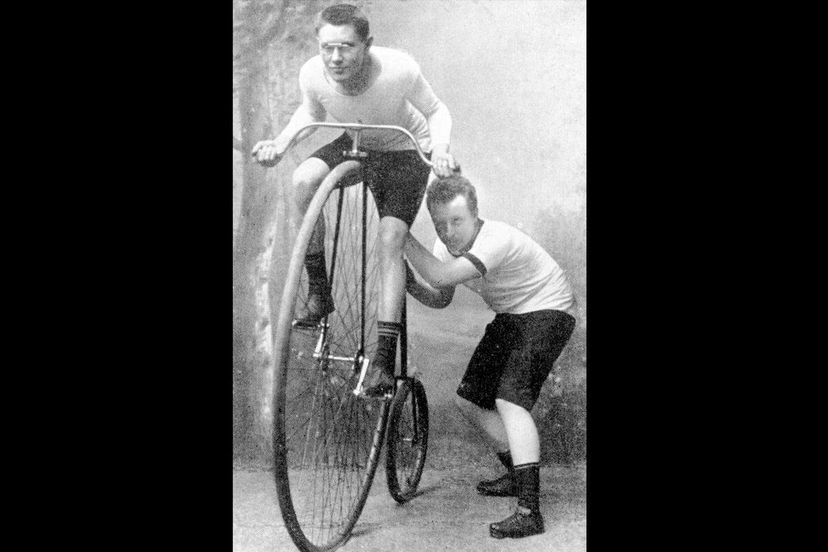 ...und Fahrräder. Mitte der 1920er Jahre ist Opel der größte Fahrradhersteller der Welt. Die fünf Söhne Adam Opels sind berühmte Radrennfahrer und tragen zur Popularität der Marke bei.   Auf diesem Foto sieht man Wilhelm Opel, der einem Sportkameraden Starthilfe gibt.