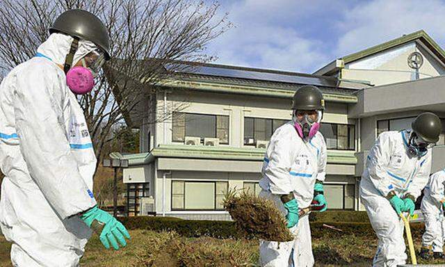 Japanische Soldaten tragen in der Gegend von Fukushima Rasen ab.