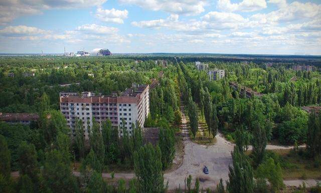 Im Vordergrund die verlassene Stadt Prypjat, im Hintergrund der Unglücksreaktor von Tschernobyl.