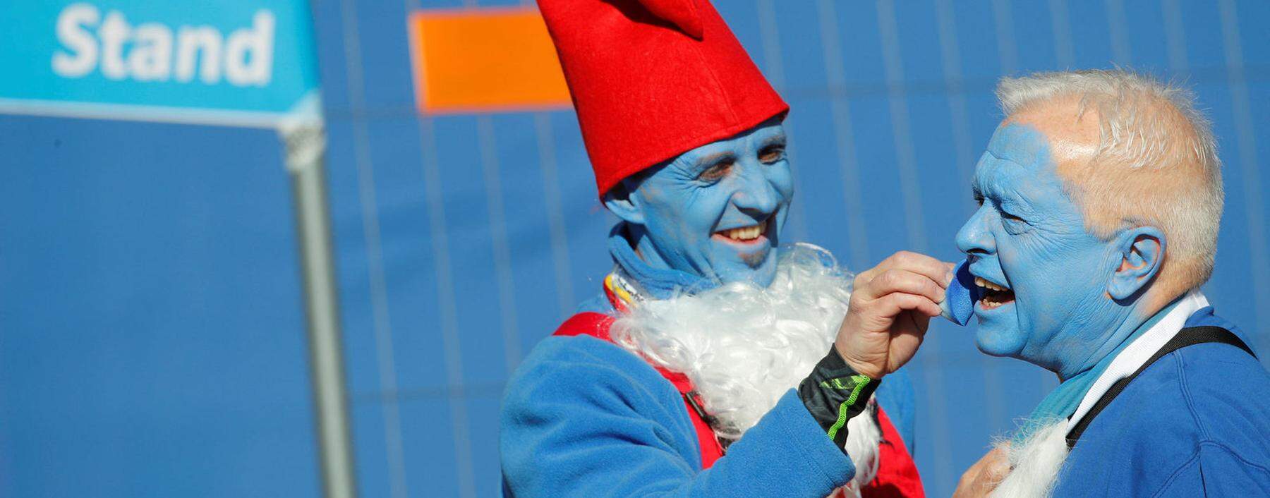 A participant dressed as a smurf paints a man's face blue in Lauchringen