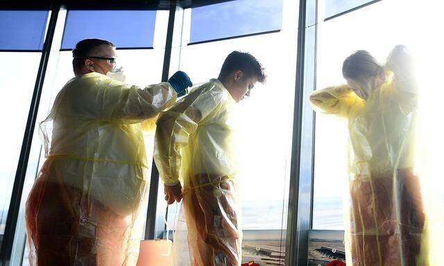Sanitäter beim Anlegen von Schutzkleidung aufgenommen im Rahmen einer PK am Flughafen Wien-Schwechat