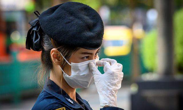 Eine Polizistin in Bangkok trägt zum Schutz vor Covid-19 Maske und Handschuhe.