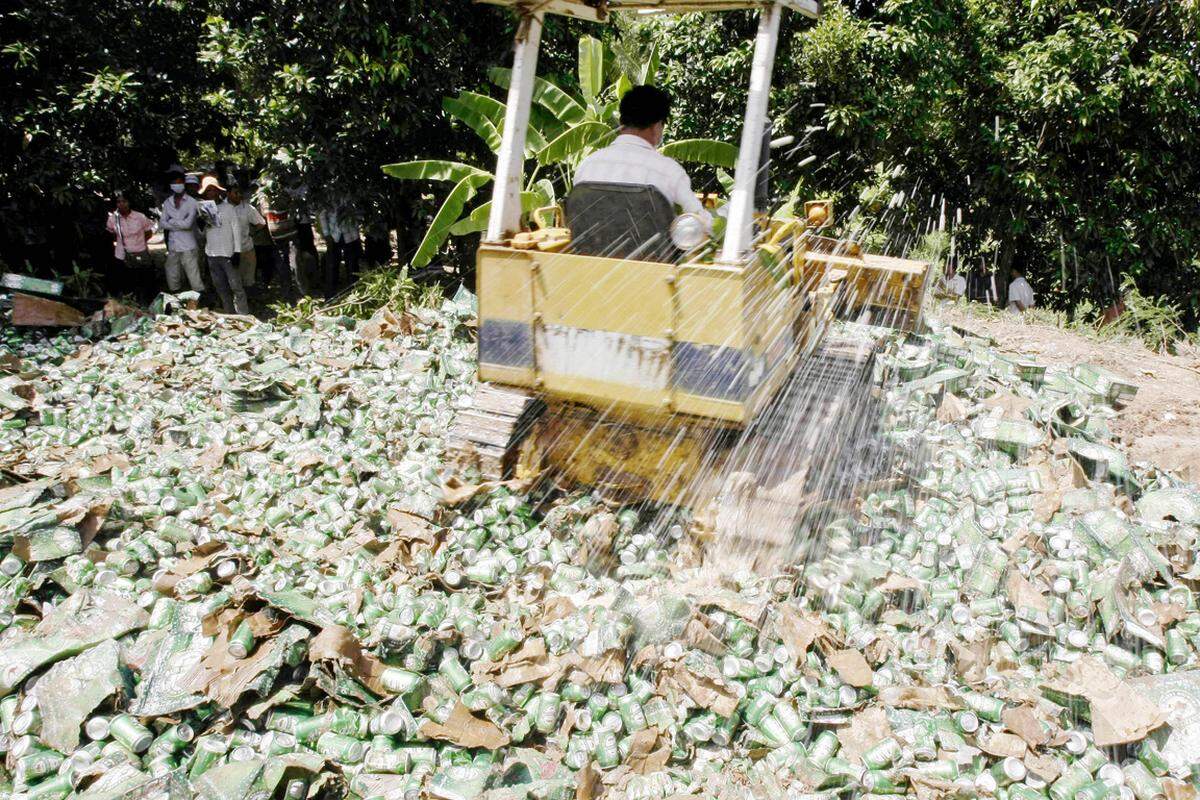 In Kambodscha macht sich ein Arbeiter mit seinem Bagger über einen Berg gefälschter Bierdosen her. Die Behörden des Landes statuieren ein Exempel und zerstören gefälschte Schmuggelware, die meist aus dem benachbarten China kommt.