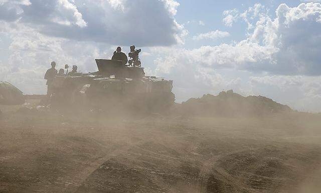 Ukrainian army servicemen around an armoured vehicle are seen through dust raised by passing vehicles near Debaltseve