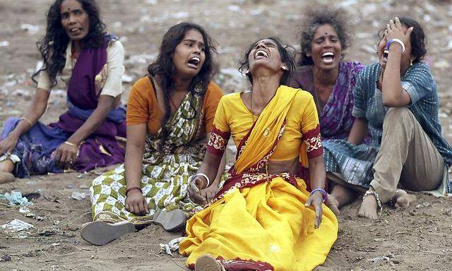 Frauen trauern in einem Dorf südlich der indischen Stadt Madras um beim Tsunami verstorbene Angehörige. Helfern bot sich bei ihrer Ankunft ein chaotisches Bild.