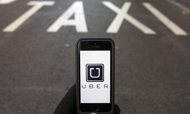 Photo illustration of logo of car-sharing service app Uber on a smartphone over a reserved lane for taxis in a street in Madrid