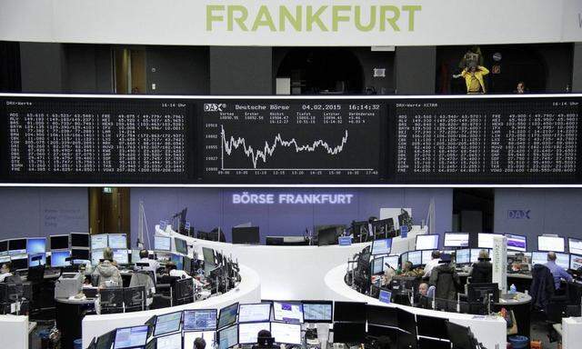 Traders are pictured at their desks in front of the DAX board at the Frankfurt stock exchange