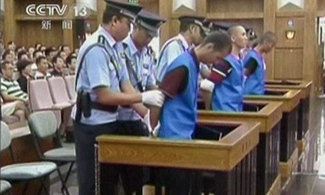 Still image of defendants being escorted by police officers at a courtroom in Kunming City