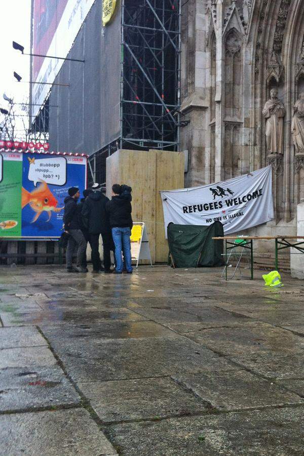 Eine Gruppe Aktivisten stehen um zirka neun Uhr Vormittag im strömenden Regen vor der Votivkirche. Sie können selbst nicht in die Kirche hinein, jegliches Klopfen an der massive Kirchentür aus Holz bleibt ungehört. Ihre Gesichter sind müde. Sie wissen nicht, wie es weiter geht.