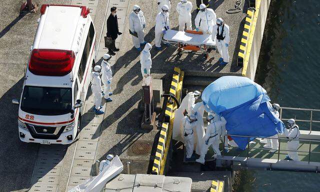 Officers in protective gear escort a person who was on board cruise ship Diamond Princess and was tested positive for coronavirus, after the person is transferred to a maritime police base in Yokohama