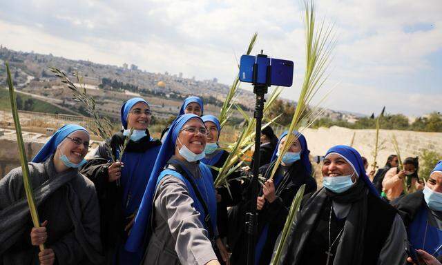 Nonnen machen ein Selfie bei der Palmsonntag-Prozession am Ölberg in Jerusalem. In diesem Jahr gelten bei den Feierlichkeiten strenge Coronaregeln. 