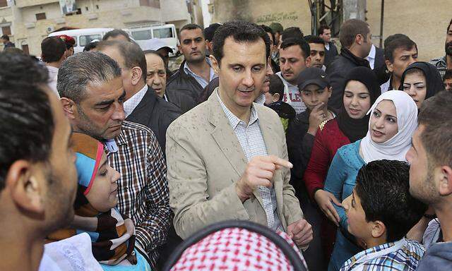 Syrian President Bashar al-Assad (C) chats with people during his visit to Ein al-Tinah village