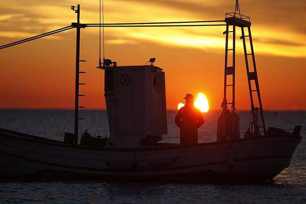 Ein Fischer vor der Küste von Malaga - dahinter die Sonnensichel.