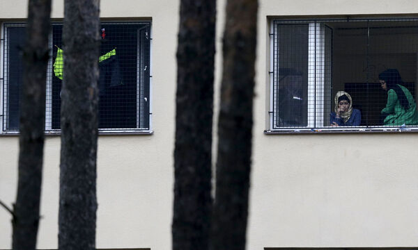 Migrants look out of a window in the Facility For Detention Of Foreigners in Bela-Jezova