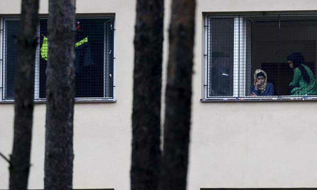Migrants look out of a window in the Facility For Detention Of Foreigners in Bela-Jezova