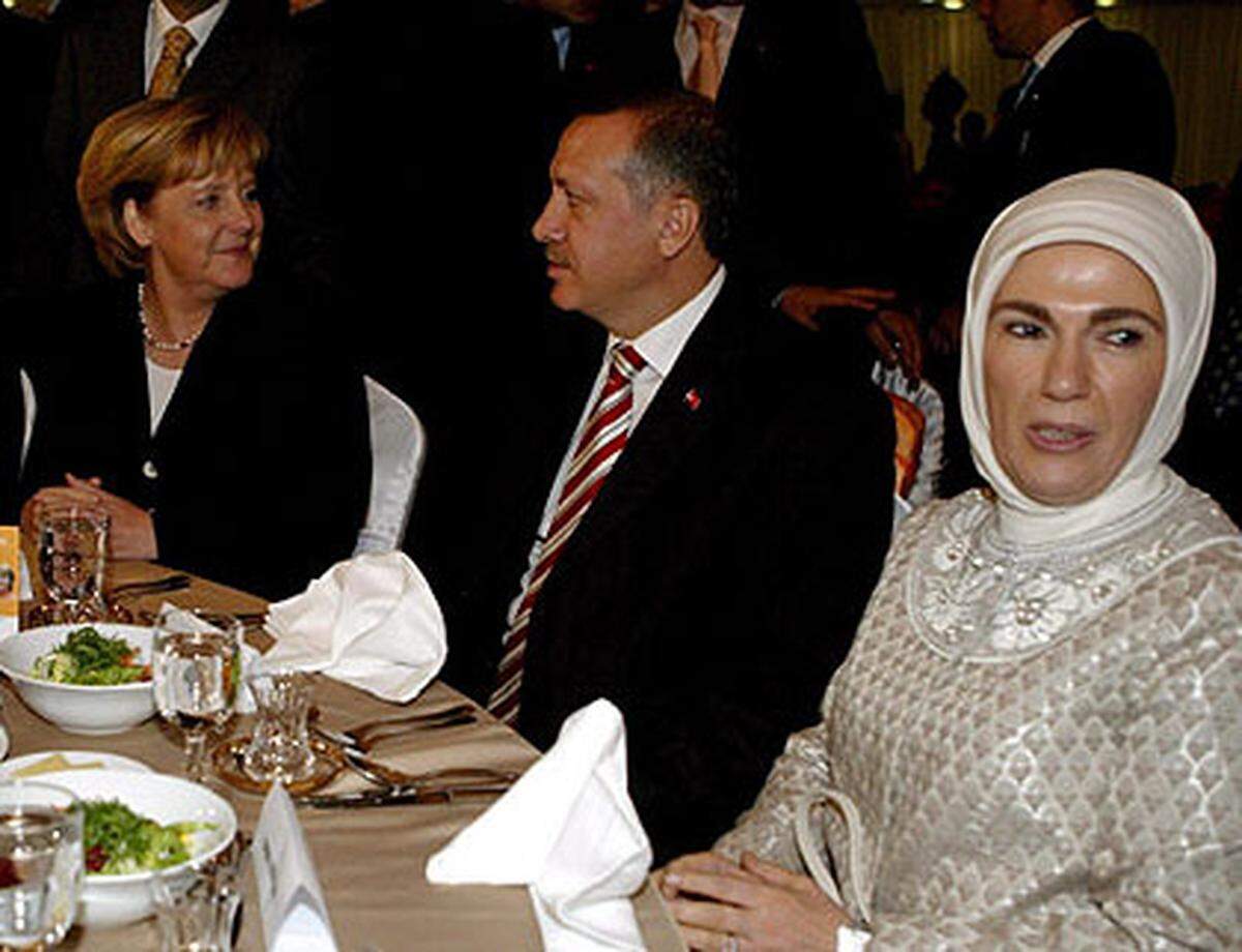 Zusammen mit seiner Frau Emine, die das als "türban" bezeichnete streng konservative Kopftuch trägt, hat Erdogan zu einem neuen Selbstbewusstsein des anatolischen Kleinbürgertums beigetragen. Seine Anhänger schätzen an ihm, dass er persönliche Frömmigkeit, wirtschaftliche Erfolge und pragmatische Politik miteinander verbindet. Für seine Gegner ist Erdogan dagegen ein ungehobelter Flegel, der in den heiligen Hallen der türkischen Regierungsspitze eigentlich nichts verloren hat. Im Bild: Erdogan mit der deutschen Kanzlerin Angela Merkel (links) und seiner Frau Emine (rechts). 