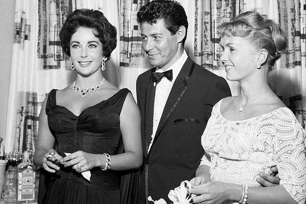 Taylor und Reynolds waren 1959 die Hauptakteure in einem der größten Liebesskandale Hollywoods. Der Sänger Eddie Fisher, mit dem Reynolds zwei Kinder hatte, ließ sich von der Blondine scheiden und wurde Liz Taylors vierter Ehemann. Die Rivalinnen versöhnten sich später.  Im Bild: Elizabeth Taylor, Eddie Fisher und Debbie Reynolds