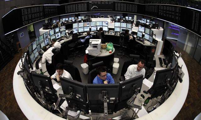 Traders are pictured at their desks in front of the DAX board at the Frankfurt stock exchange