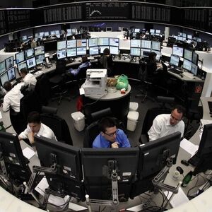 Traders are pictured at their desks in front of the DAX board at the Frankfurt stock exchange