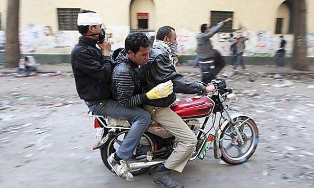 Protesters transport an injured fellow protester on a motorcycle during clashes with riot police alon