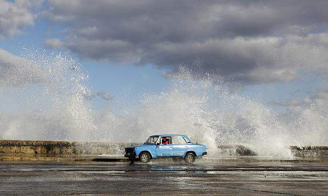 A Russian-made Lada car drives past as waves break on Havana´s seafront boulevard ´El Malecon´