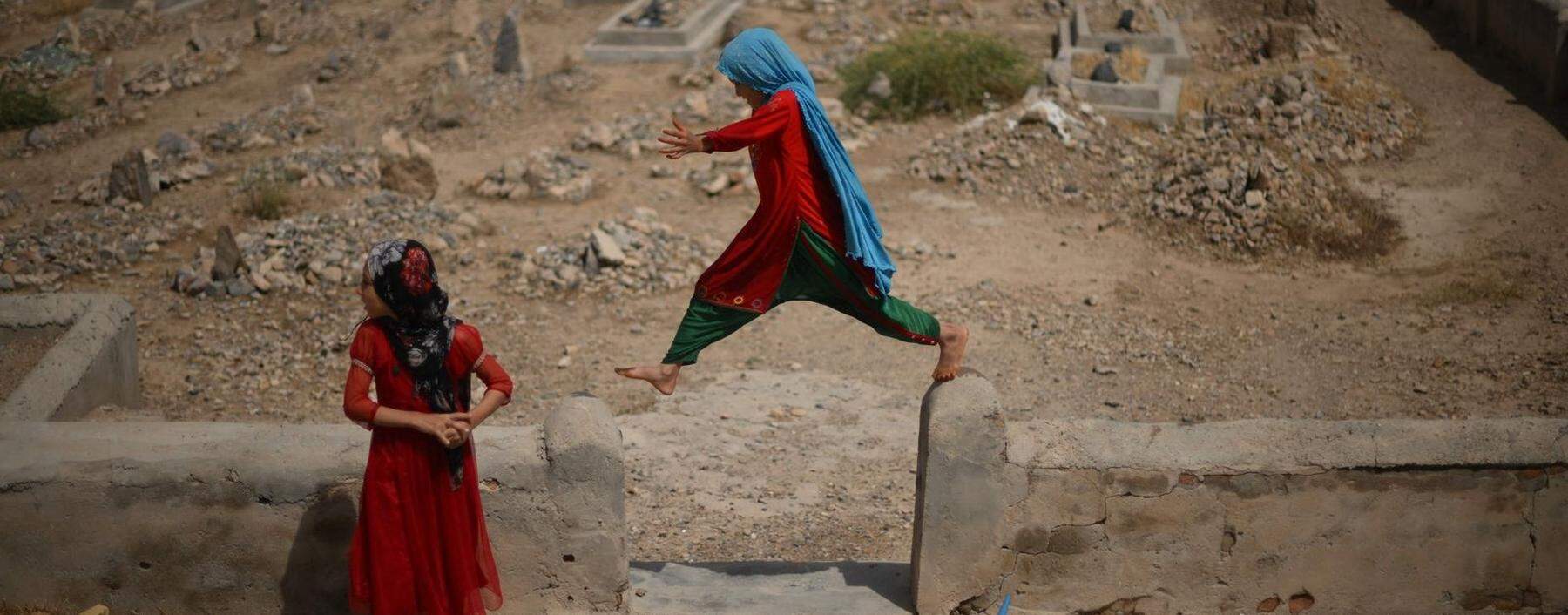Eine ungewisse Zukunft unter der Herrschaft der Taliban. Afghanische Mädchen spielen vor einem Friedhof in Kandahar. 