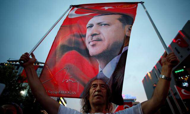 A supporter holds a flag depicting Turkish President Tayyip Erdogan during a pro-government demonstration in Ankara, Turkey