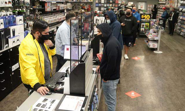 People line up inside a GameStop store to purchase a Sony PS5 gaming console