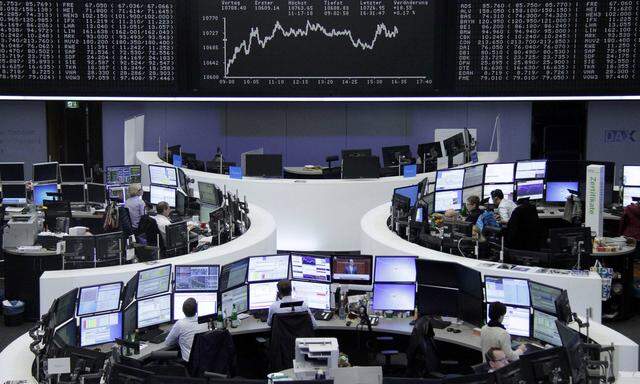 Traders work at their screens in front of the German share price index DAX board at the stock exchange in Frankfurt