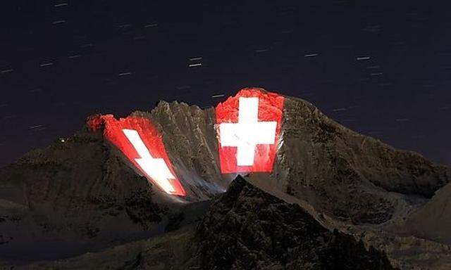 A giant light installation of the flag of Switzerland illuminates the north face of the Jungfrau moun