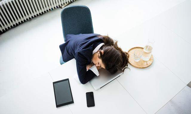 Overworked businesswoman sleeping on laptop in office, top view