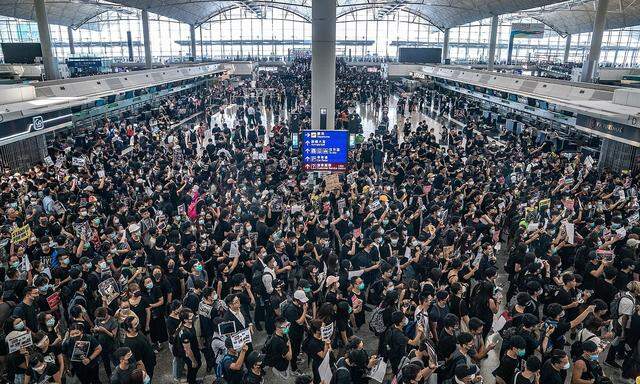 In schwarz gekleidete Demonstranten besetzen den Hongkonger Flughafen.