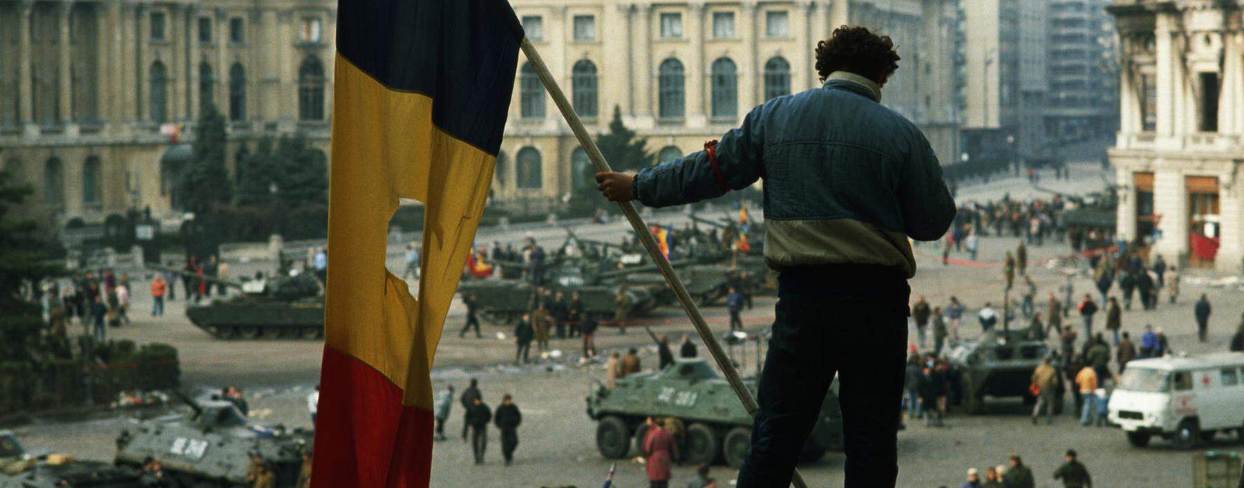 Auf dem Platz vor dem Bukarester Regierungspalast, Dezember 1989. Aus rumänischen Fahnen schnitt man damals die Insignien der Kommunistendiktatur.