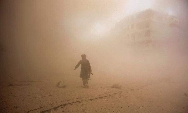 A rebel fighter runs through dust towards an area damaged by what activists said were barrel bombs dropped by warplanes loyal to Syria´s President Assad in Aleppo