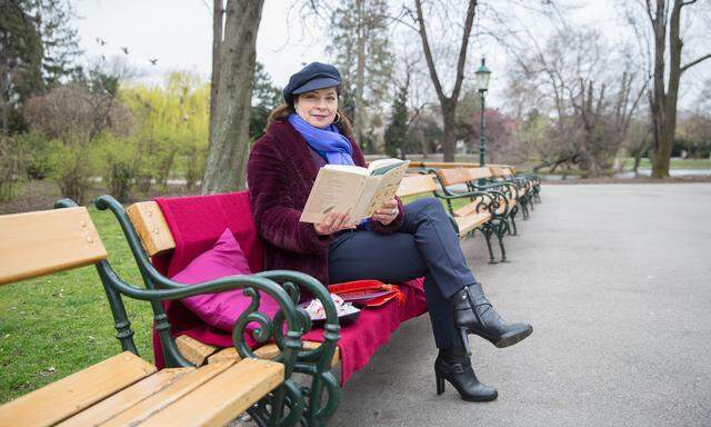 Ingrid Lassnig liest Parkbesuchern auf einer Bank im Stadtpark vor.