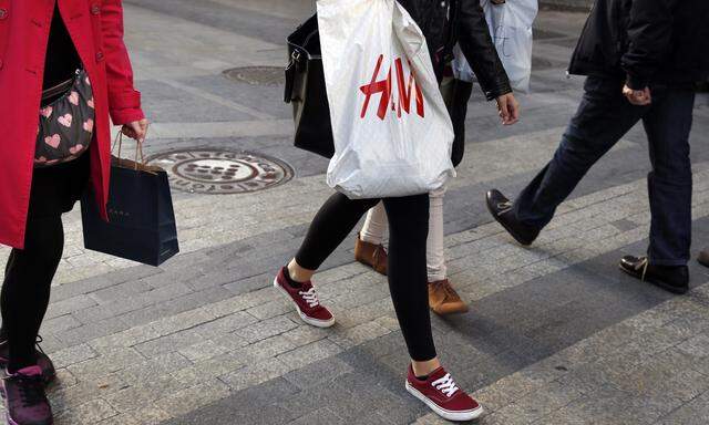 Women with Zara and H&M shopping bags walk at a shopping district in central Madrid