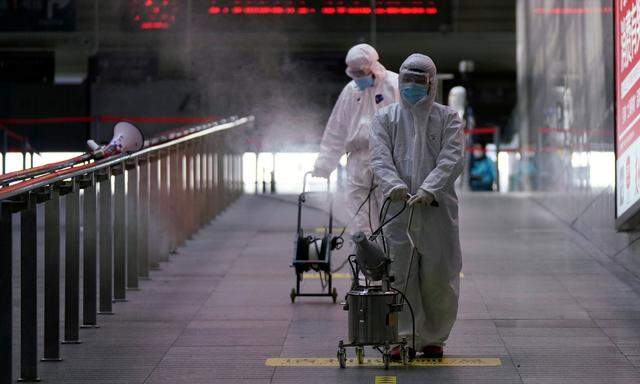 Arbeiter mit Desinfektionsgeräten in einem Bahnhof in Shanghai.