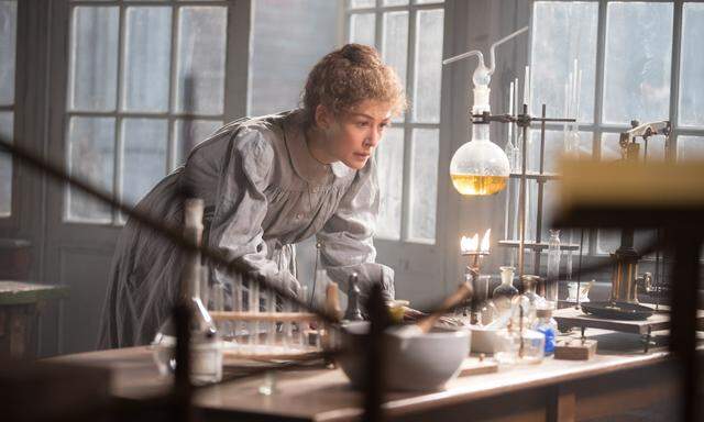 Rosamund Pike gibt Marie Curie mit dem Stolz einer Besessenen, die noch nicht weiß, dass ihre eigene Entdeckung ihren Körper zerstören wird.