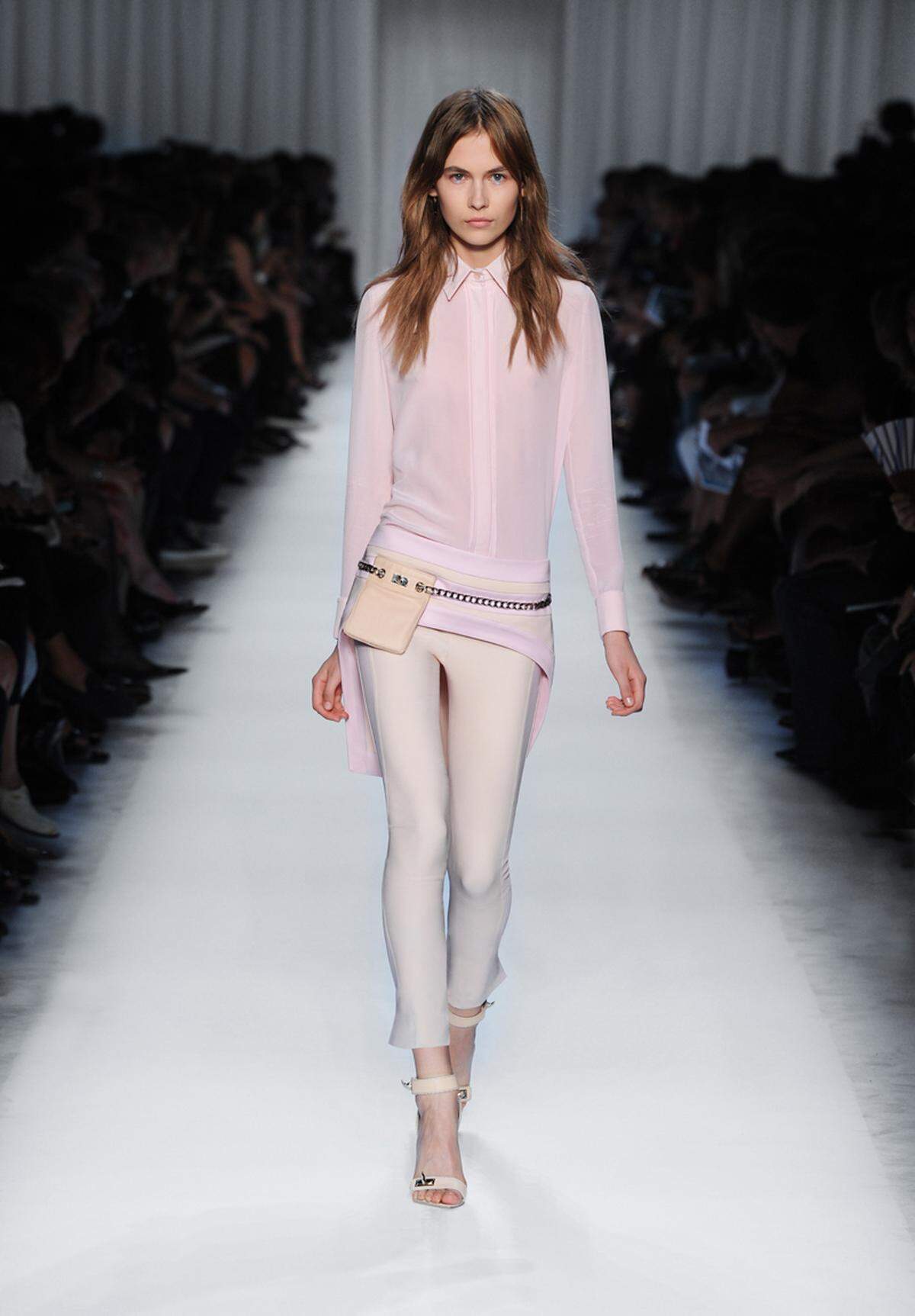 Zu einer weißen Hose wird die rosafarbene Bluse bei Givenchy getragen.
