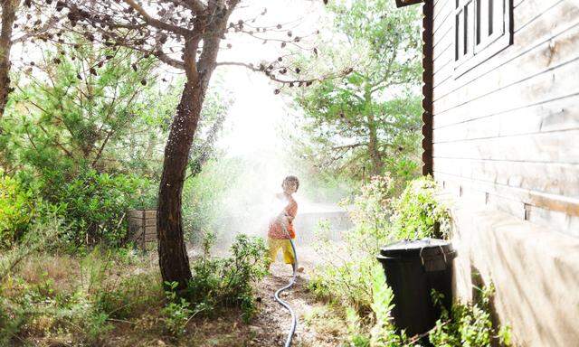 Kind spielt mit Gartenschlauch