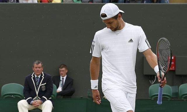 Jurgen Melzer of Austria and the umpire argue about the condition of the grass during his men's singles tennis match against Sergiy Stakhovsky of Ukraine at the Wimbledon Tennis Championships, in London