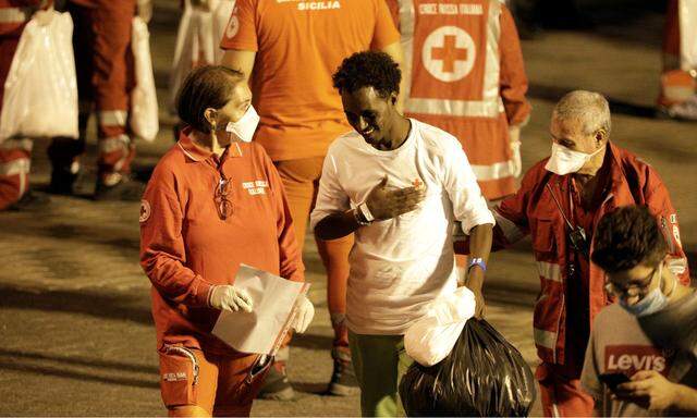 A migrant is helped by Red Cross memebrs after disembarking from Italian coast guard vessel ´Diciotti´ at the port of Catania